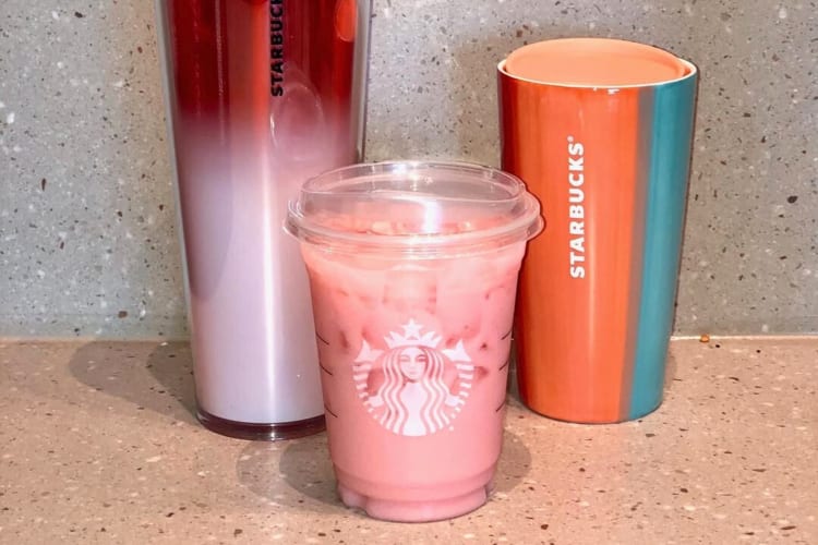 An Iced Guava Passionfruit Drink in between two Starbucks stainless steel cups