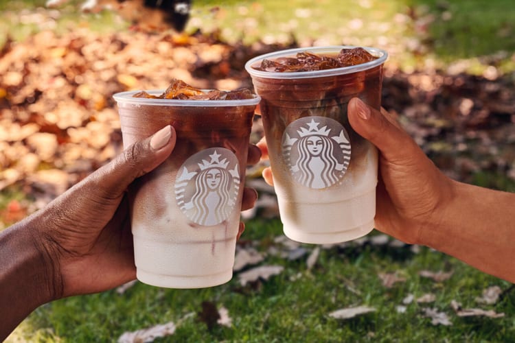 Two hands clinking two Starbucks cups together during a toast