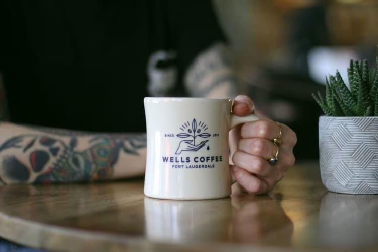 A Wells Coffee mug on a table. 