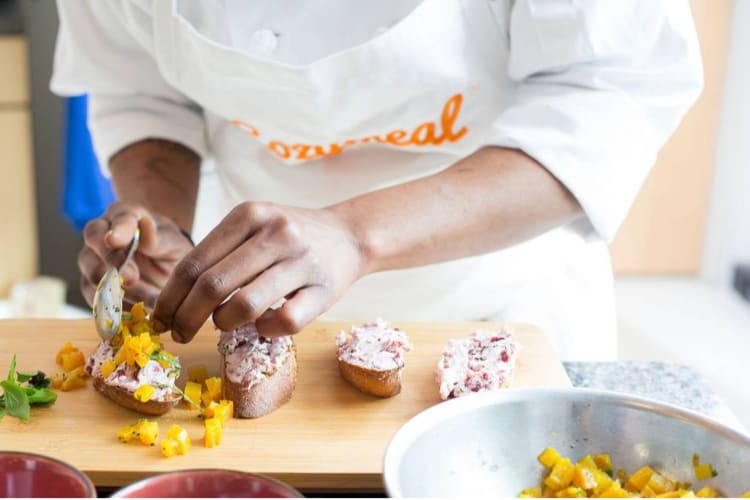 a chef garnishing a platter of toast rounds