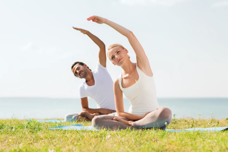Couple practicing yoga at a park
