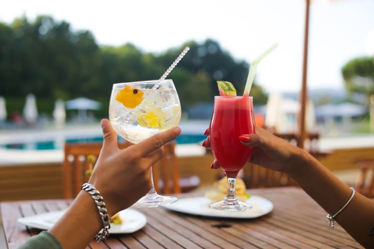 A couple holding two cocktails 