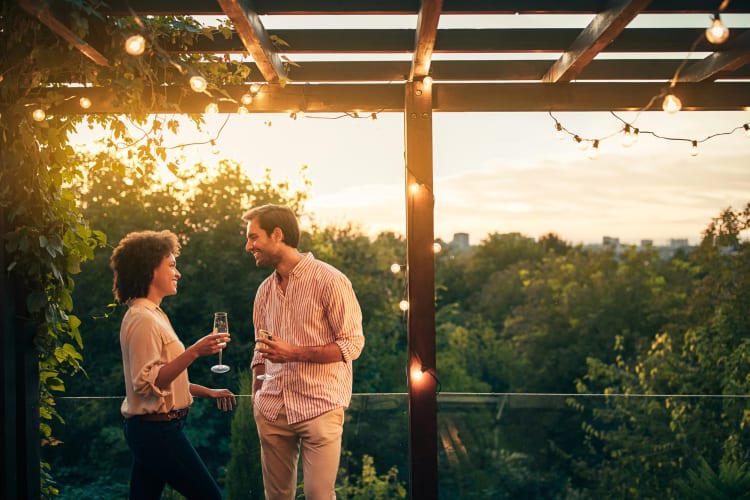 A man and woman talking out on a terrace while holding Champagne glasses