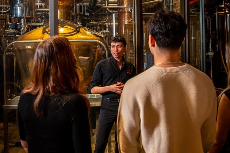 A guide talking to a group of people during a tour at Great Jones Distilling Co.