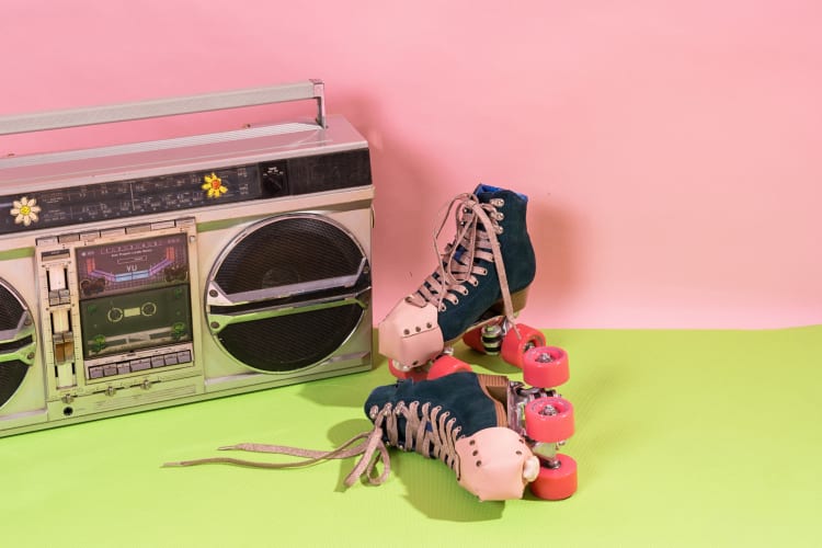 Roller skates next to a boom box on a green and pink background