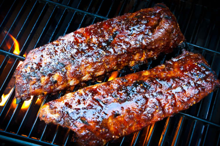 Ribs with barbecue sauce cooking on a grill 