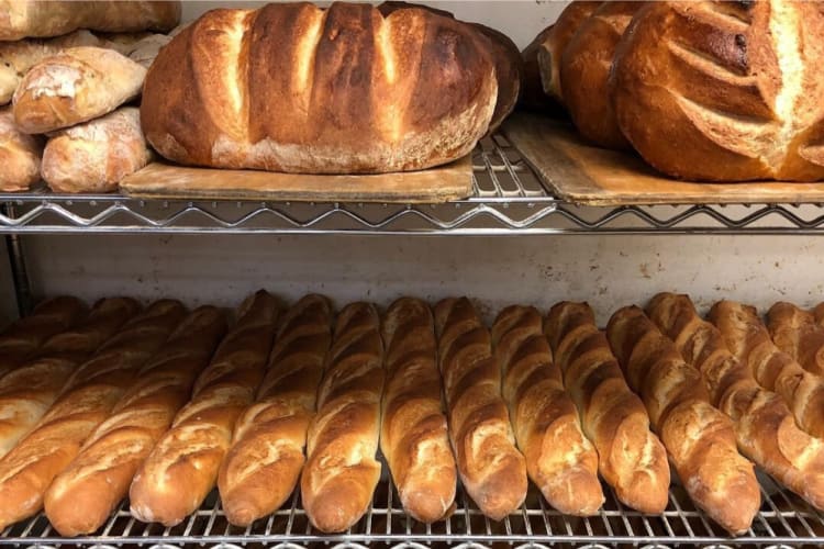 A selection of baguettes and bread loaves on shelving racks