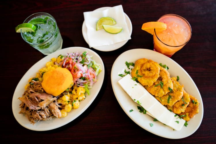 Two plates of Ecuadorian food next to two fruity drinks