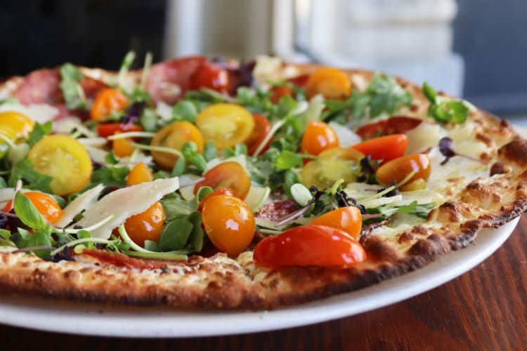 A pizza with cherry tomatoes and green garnish