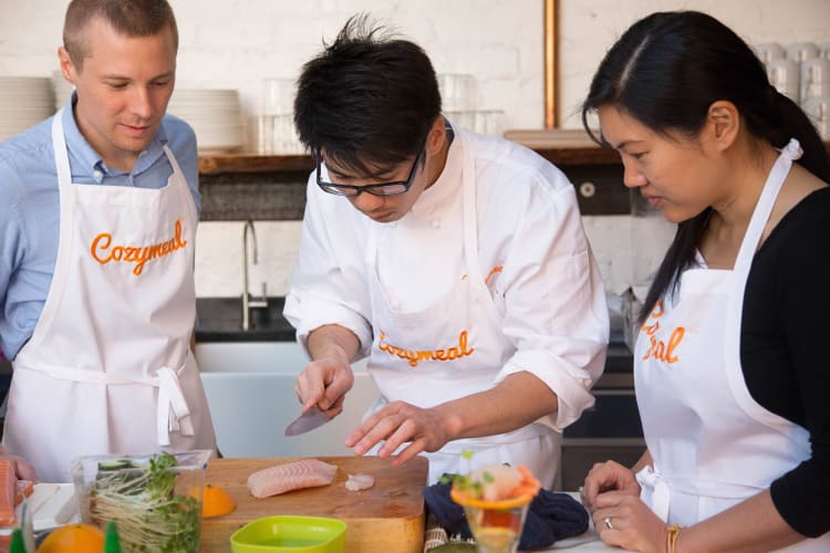 Two people taking a cooking class with a chef, booked through Cozymeal