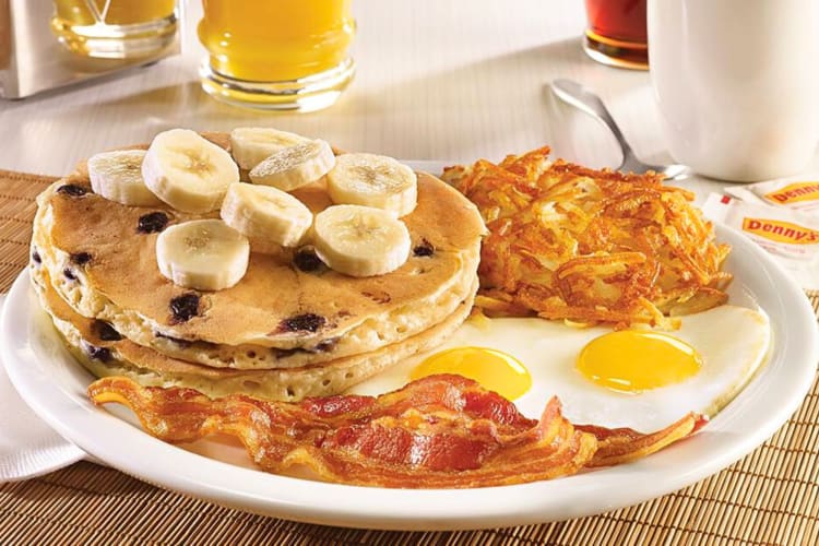 Pancakes topped with banana slices, next to bacon, eggs and a hash brown, from a diner in Fort Worth