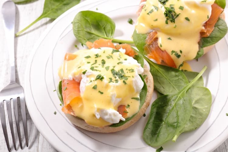 egg Benedict with smoke salmon and baby spinach on a ceramic plate