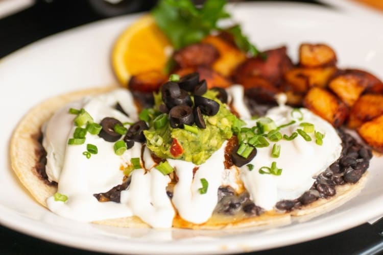 Two poached eggs over grilled corn tortillas with black beans, cheese and salsa