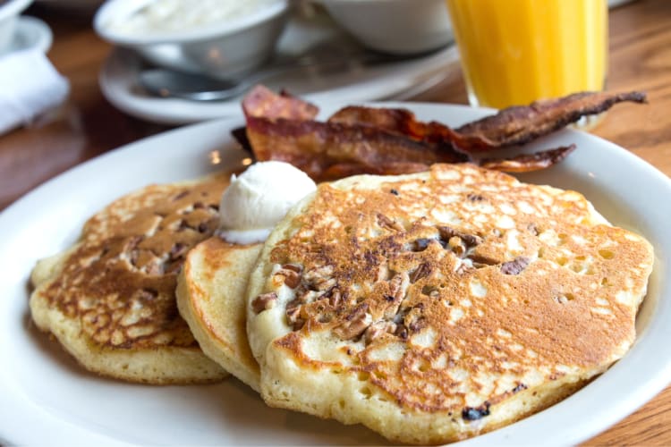 Traditional hotcakes topped with butter and served with bacon on the side