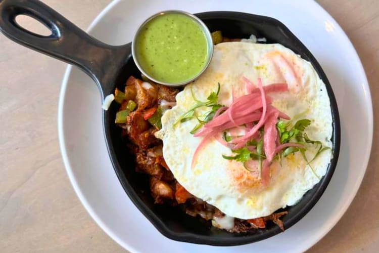Birria skillet topped with eggs and pickled onions