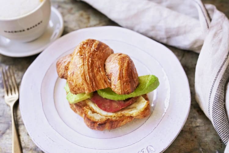 Cornetto, avocado, tomato and egg sandwich on a plate