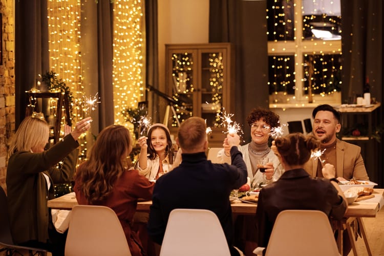 A group of seven people holding sparklers up during a dinner party