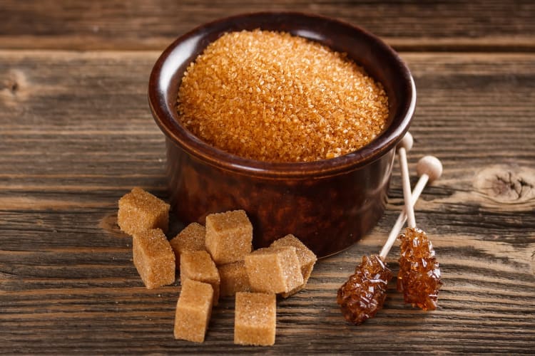 a bowl of brown sugar beside the cube and crystallized form