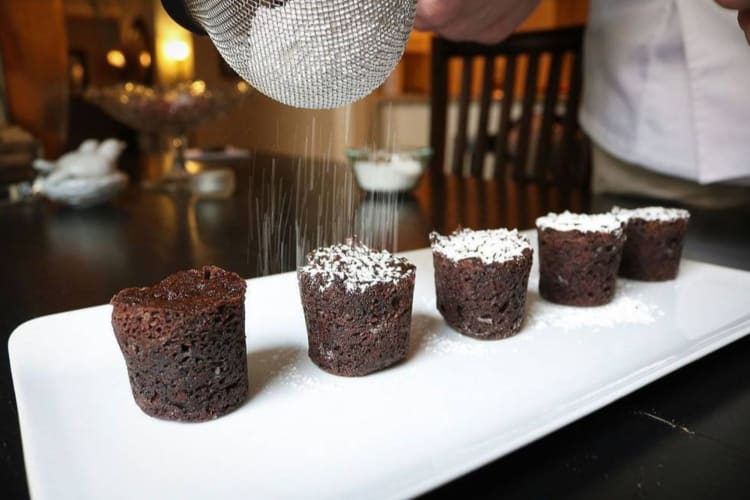 a chef shaking powdered sugar onto brownie bites