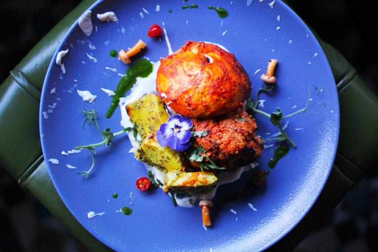 Indian food on a blue plate garnished with a flower