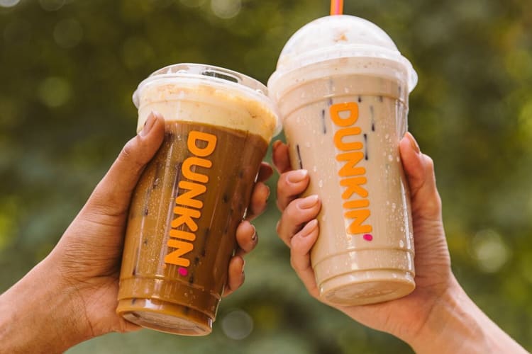 Two hands holding two iced coffees from Dunkin' Donuts