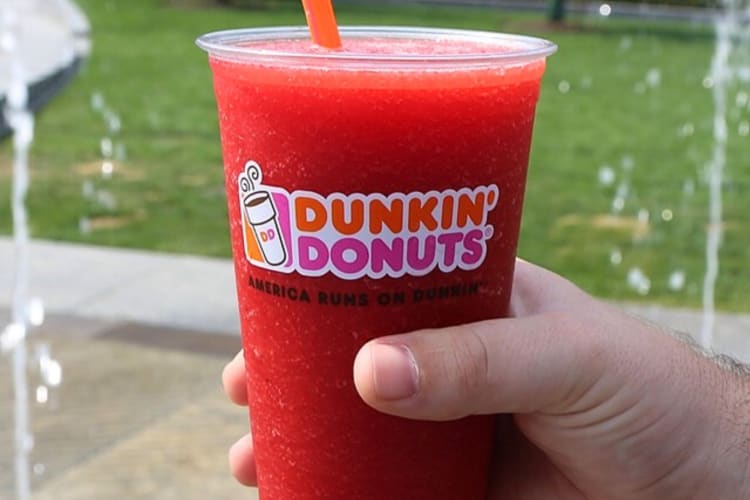 A hand holding a strawberry iced drink from Dunkin' Donuts
