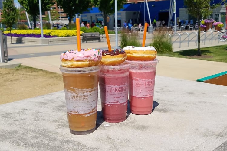 Three drinks topped with three doughnuts from Dunkin' Donuts