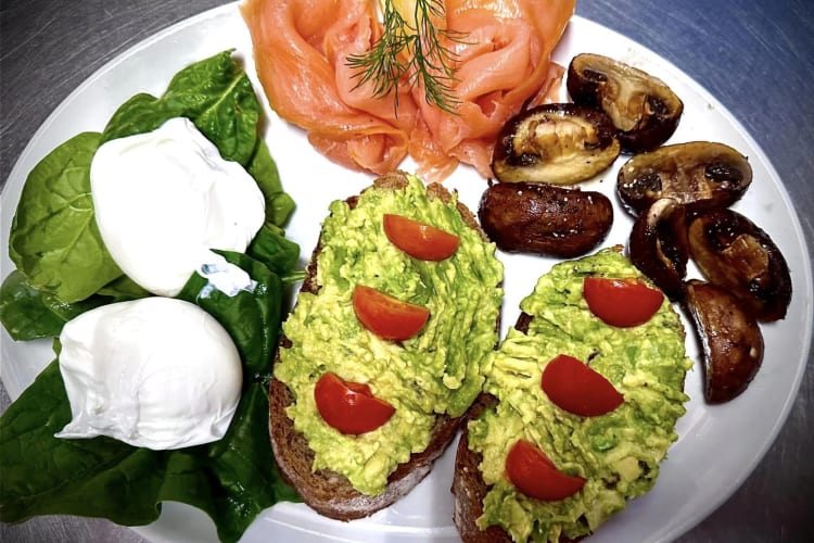 Poached eggs on a bed of spinach, smoked salmon, avocado and tomato on toast with grilled mushrooms.