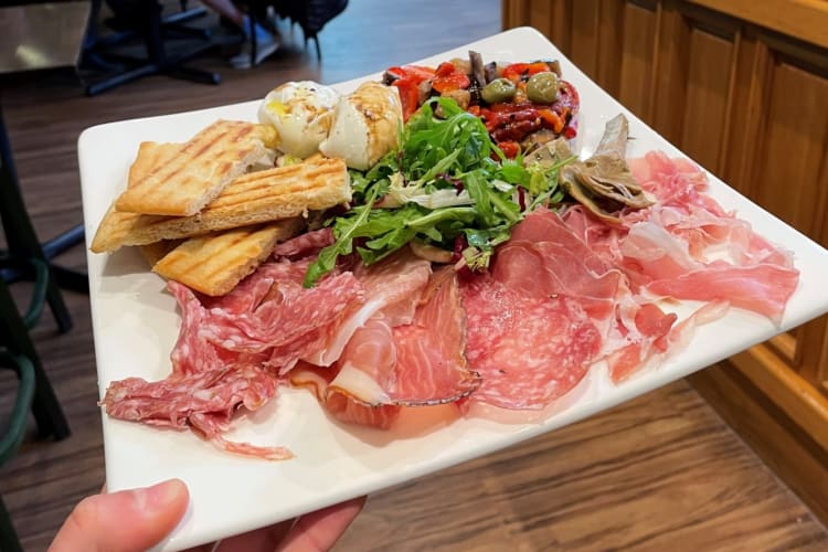 a waiter holding a platter of assorted antipasti