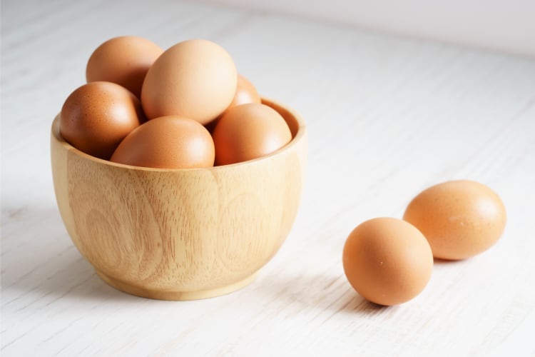 Eggs on a wooden bowl and a table 