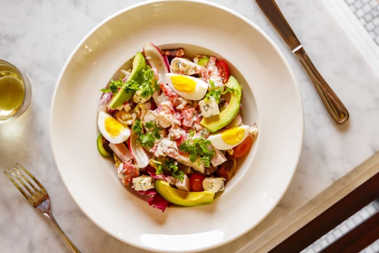 Lobster cobb salad served with avocado on a ceramic plate