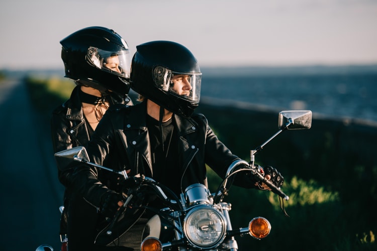 A man and woman on a bike looking out to the ocean, which is a great first date idea