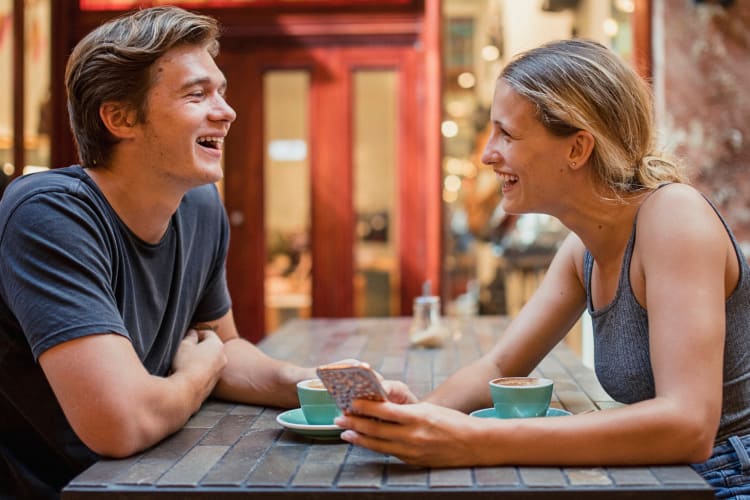 A man and woman laughing and chatting during a coffee date