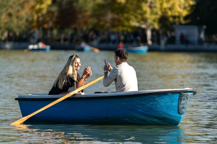 A man taking a photo of a woman while out in a rowing boat