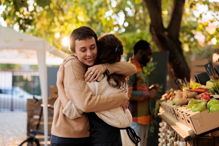 Two people hugging at a farmers market, which is a great place to go for a first date idea