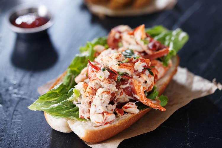 A lobster roll on a slate surface.