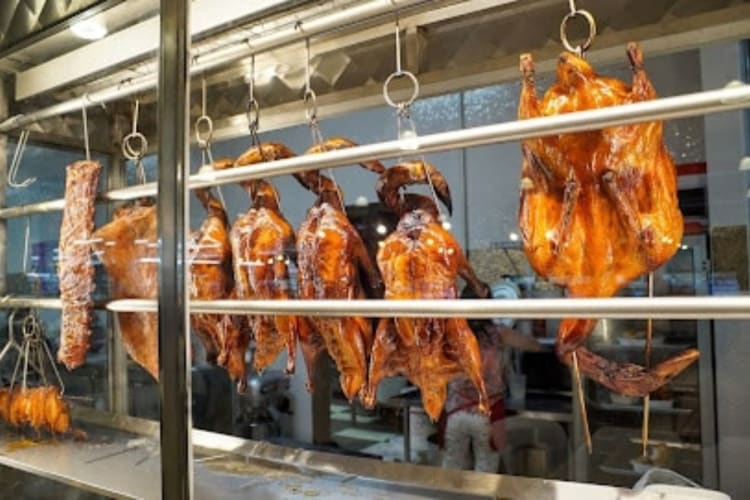 Roasted meats hanging from a stall at a Chicago food hall.