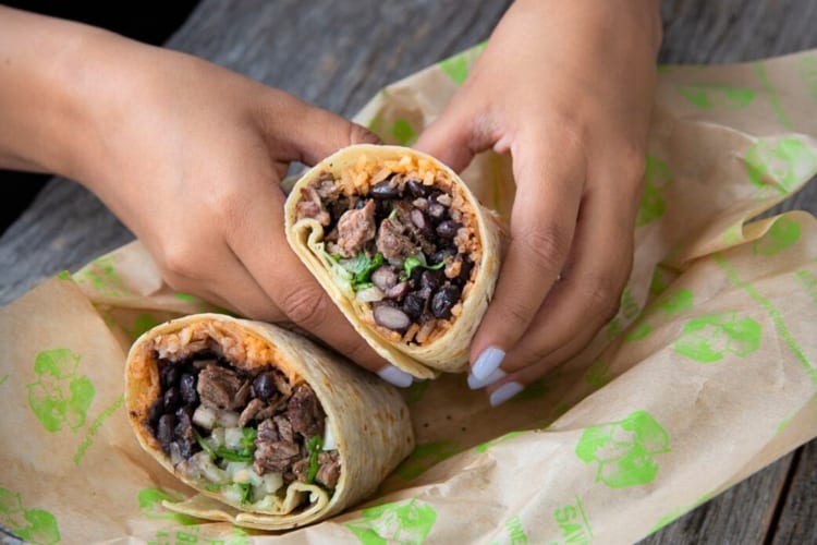 Hands holding half of a burrito, which is free birthday food from Baja Fresh Mexican Grill