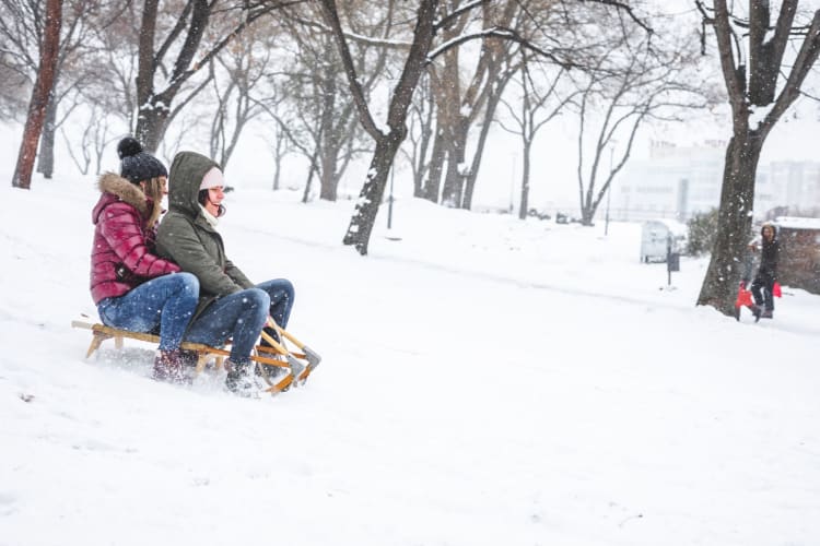 Young women sledding downhill in the snow.