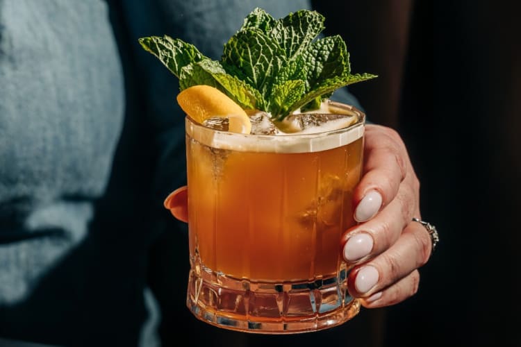 A hand holding a midnight stinger from Gus’ Sip & Dip