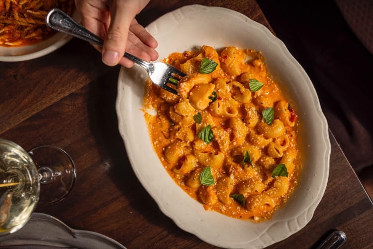 A hand using a fork to pick up pasta from Gilt Bar, a fun restaurant in Chicago
