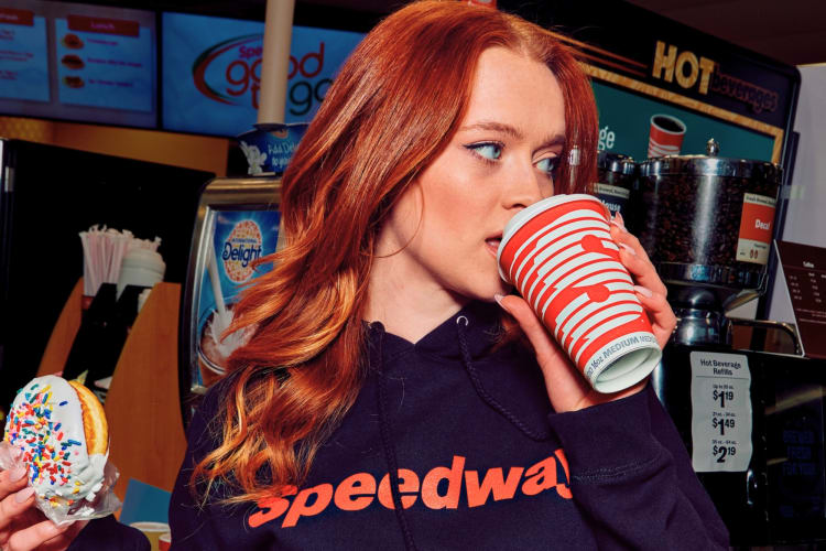 Girl drinking Speedway coffee with a donut