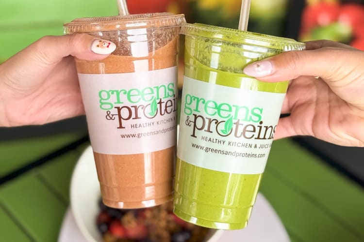 Two hands holding two smoothies from Greens and Proteins in Las Vegas