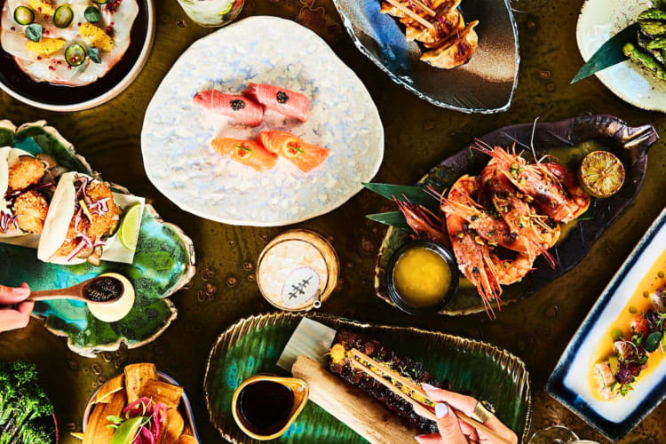 Hands eating from various meals at SUSHISAMBA, a gluten-free restaurant in Las Vegas