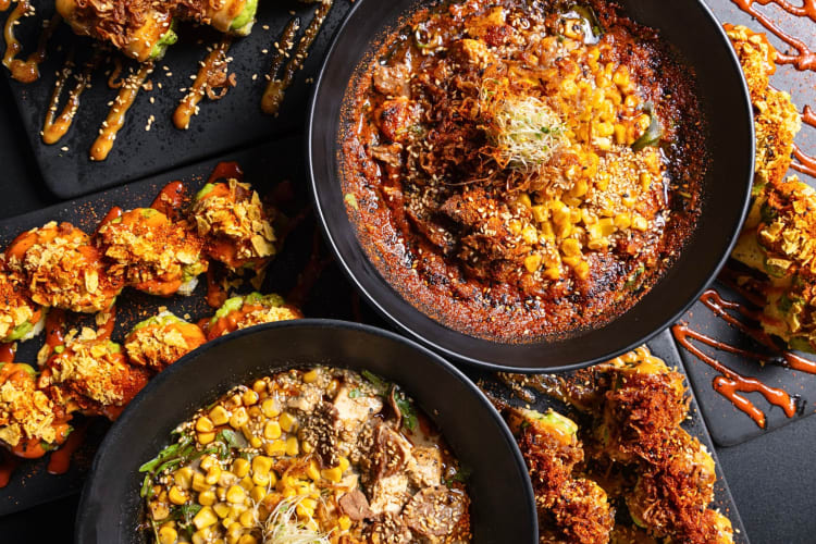 Two bowls of ramen and plates of sushi from Redwhite Boneless Ramen