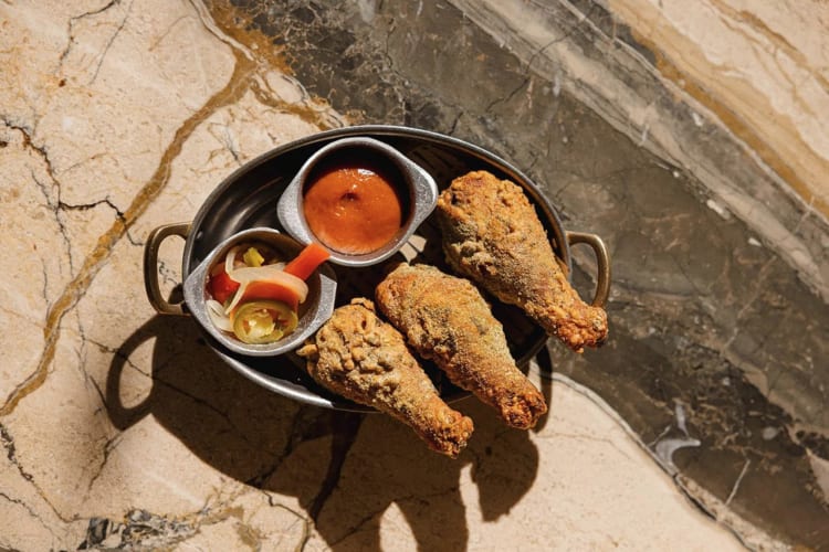 Three fried chicken drumsticks, sauce and relish from Si! Mon