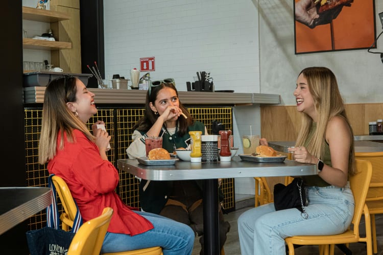 Three female friends chatting, laughing and eating at a restaurant