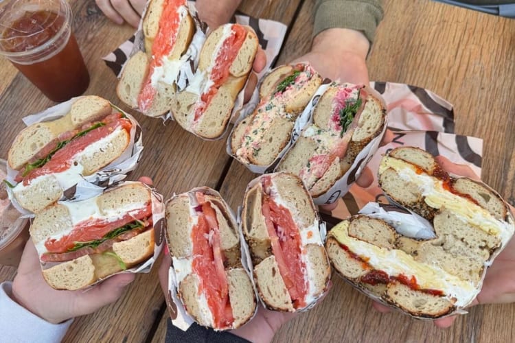 Hands holding bagels from Modern Bread and Bagel, a gluten-free restaurant in NYC