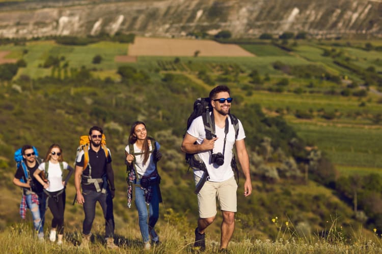 a group of adults take a casual hike up a hill in the sunshine