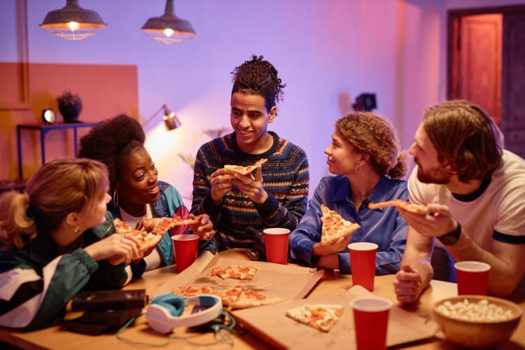 a group of people chat while having a pizza party together